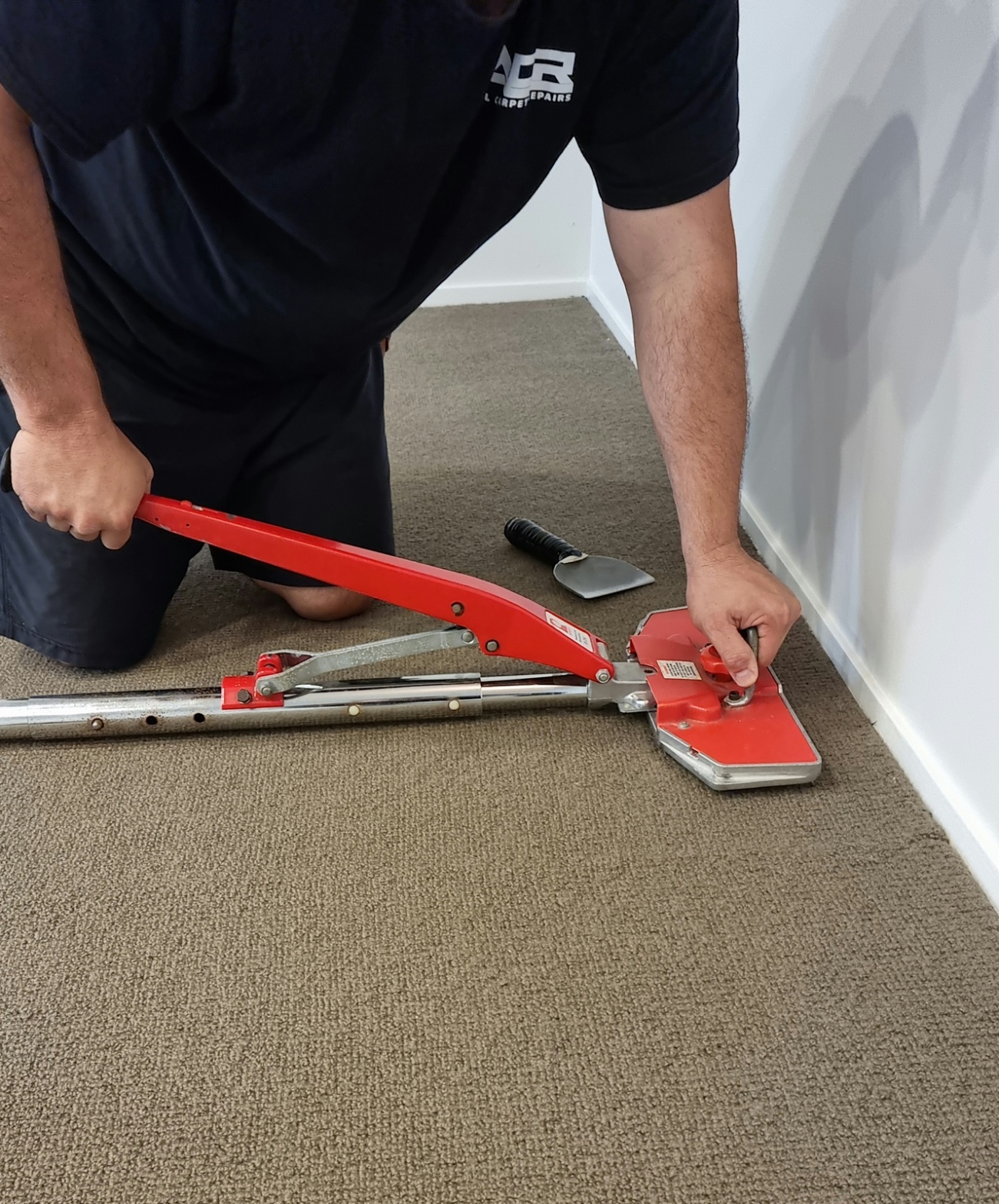 ACR technician using power stretcher to restretch carpet